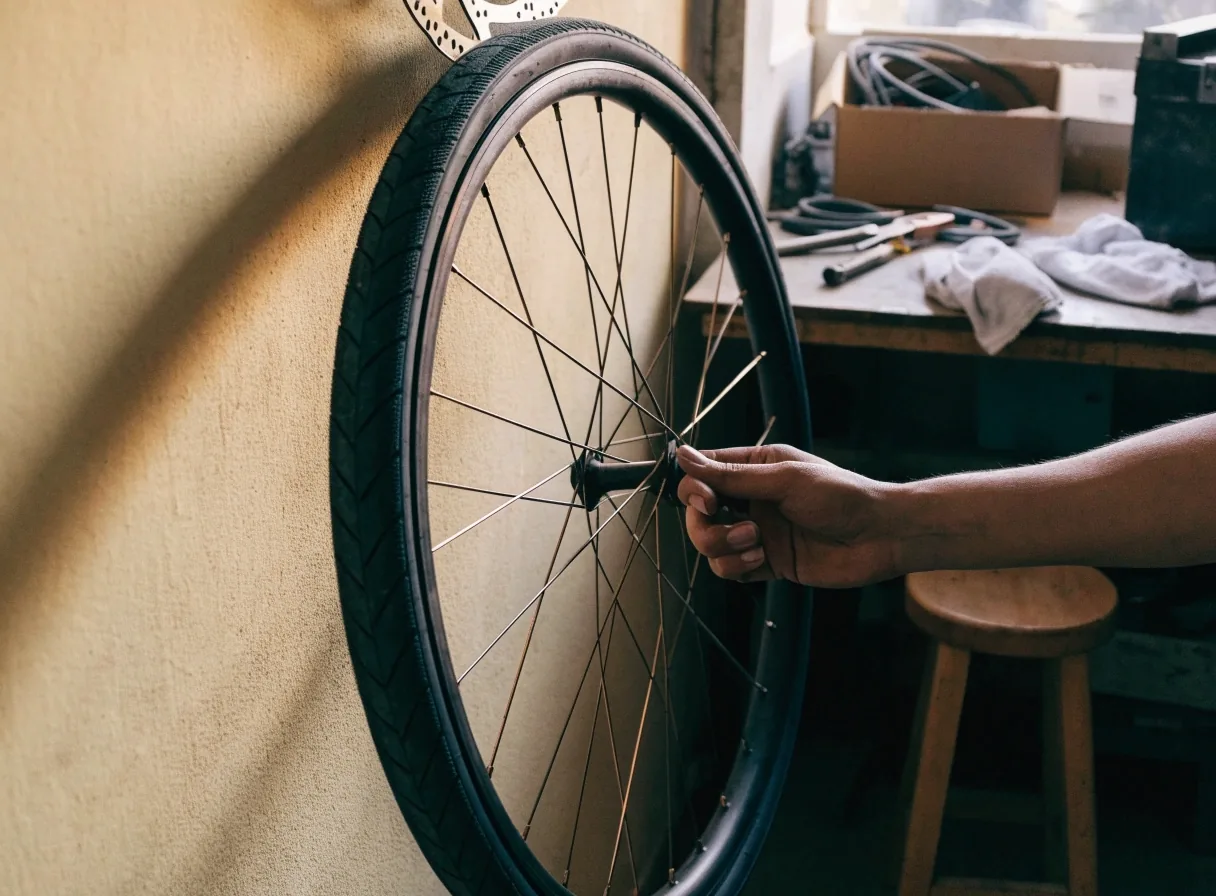 Rueda de bicicleta usada apoyada contra una pared clara